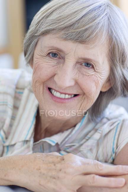 Retrato de mujer mayor feliz relajándose en el sofá
. - foto de stock