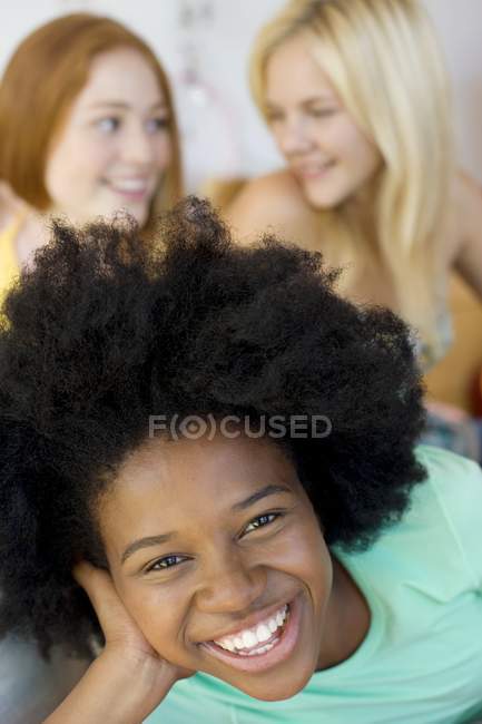 Three cheerful teenage girls relaxing and chatting together in bedroom. — Stock Photo