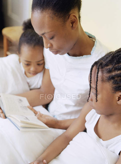 Mother reading book to elementary age daughter and son at bedtime. — Stock Photo