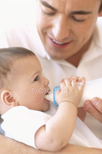 Pai alimentando bebê menina com garrafa de leite . — Fotografia de Stock