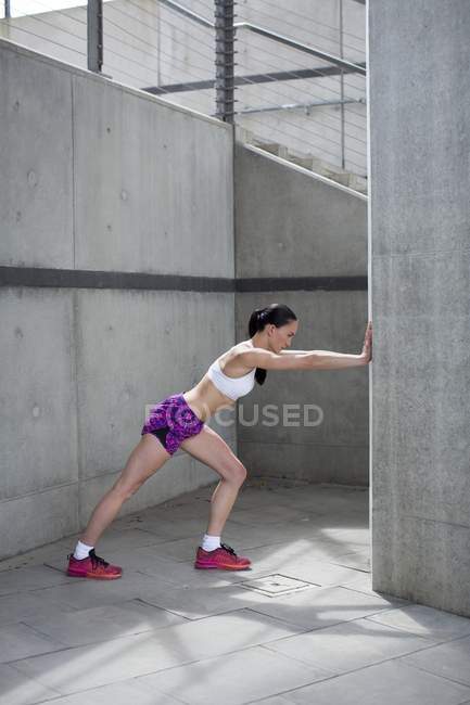 Woman stretching against wall — Stock Photo