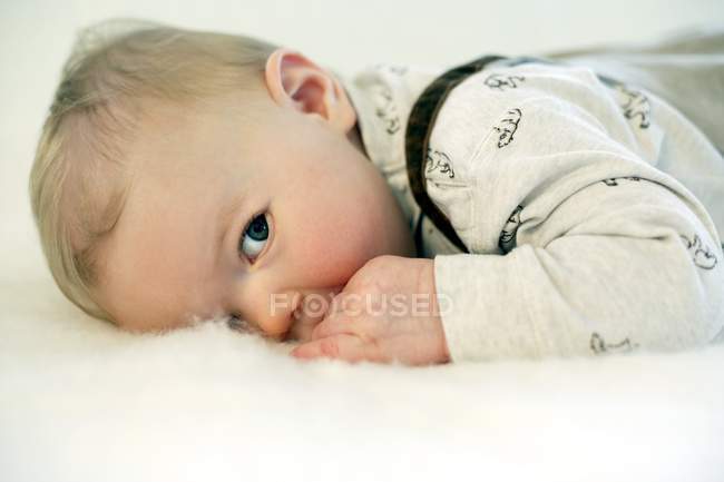 Bébé garçon couché sur le devant au lit . — Photo de stock