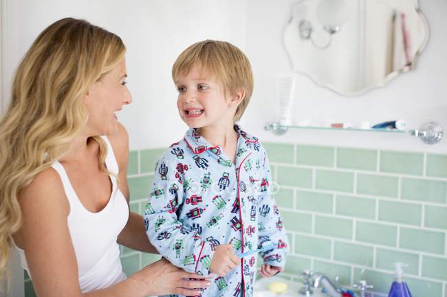 Fils préscolaire brossant les dents avec la mère dans la salle de bain . — Photo de stock
