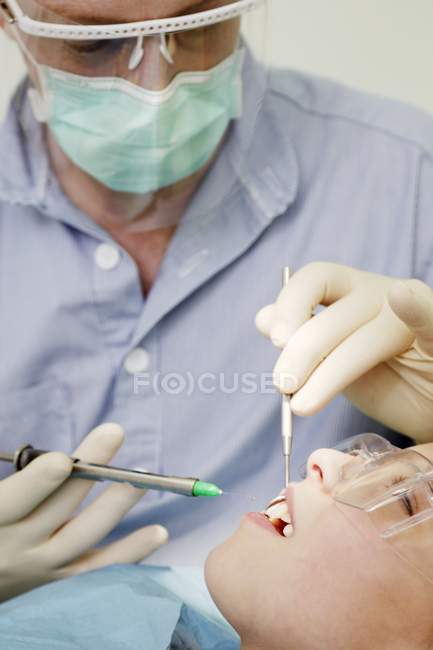Dentista haciendo inyección en goma de mascar de niña . - foto de stock