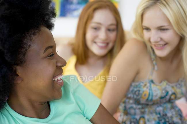 Três adolescentes alegres rindo enquanto saem dentro de casa . — Fotografia de Stock