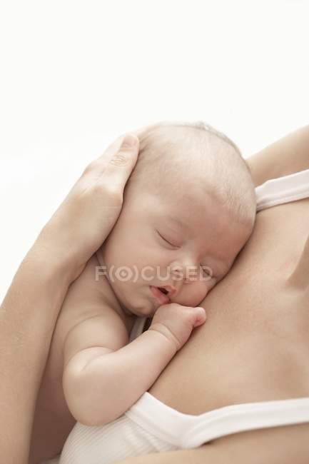 Primo piano del bambino addormentato tra le braccia materne
. — Foto stock