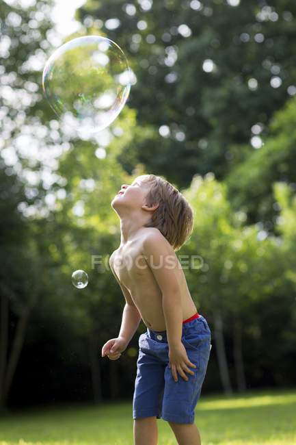 Junge beobachtet Blase im Garten. — Stockfoto