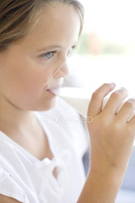 Mädchen im Grundschulalter trinkt Milch aus Glas. — Stockfoto