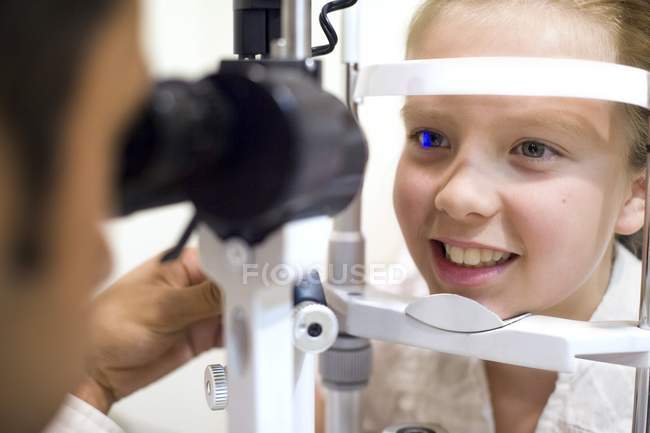 Óptico usando lámpara de hendidura para el examen ocular niña preadolescente . - foto de stock