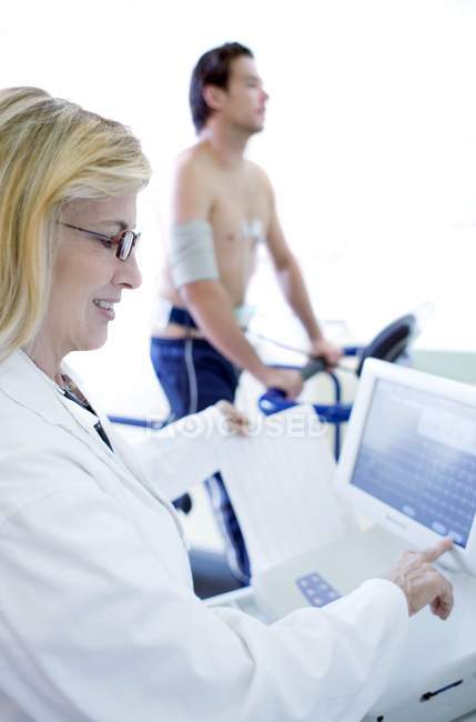 Mature doctor testing heart of male athlete on treadmill. — Stock Photo