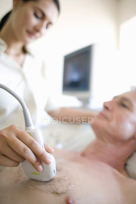 Senior patient undergoing heart ultrasound scanning by female doctor. — Stock Photo
