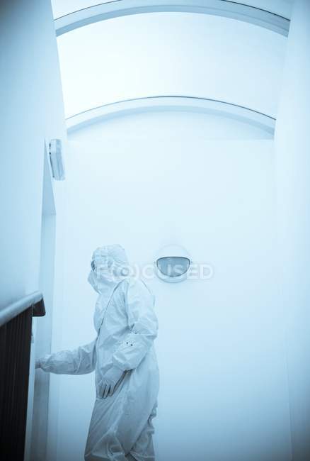 Vista lateral do cientista masculino na porta de abertura do terno de isolamento branco . — Fotografia de Stock