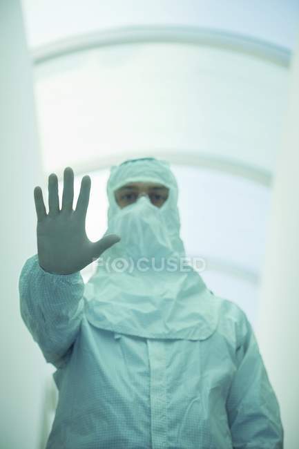 Вчений в захисному костюмі робить стоп жест в коридорі . — стокове фото