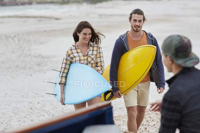 Paar spaziert mit Surfbrettern am Strand. — Stockfoto