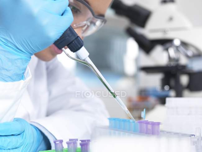 Female laboratory worker filling vials with pipette, close-up. — Stock Photo
