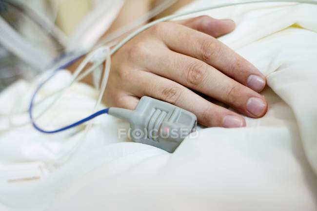 Blood oxygen monitor on finger of patient in intensive care ward, close-up. — Stock Photo