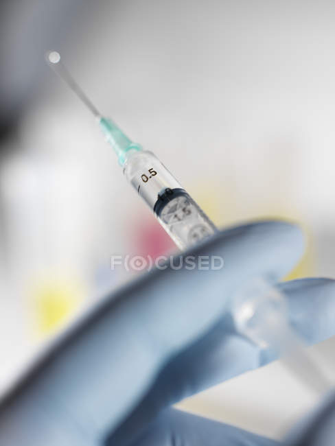 Close-up of gloved hand holding hypodermic syringe. — Stock Photo