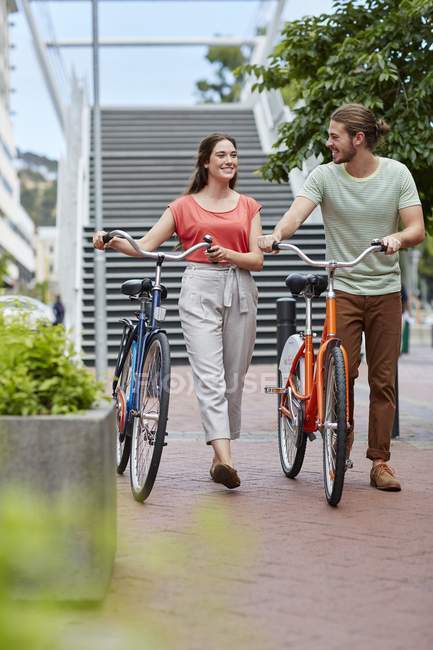 Jovem casal andando com bicicletas na rua . — Fotografia de Stock