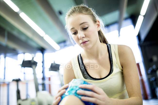 Woman holding ice pack on injured knee. — Stock Photo