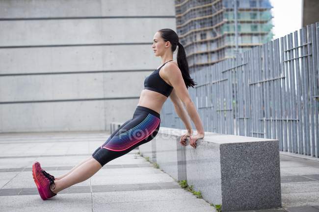 Woman stretching on stone bench outdoors — Stock Photo