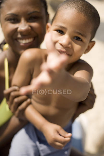Mutter umarmt Sohn mit Wurfgeste am Strand. — Stockfoto