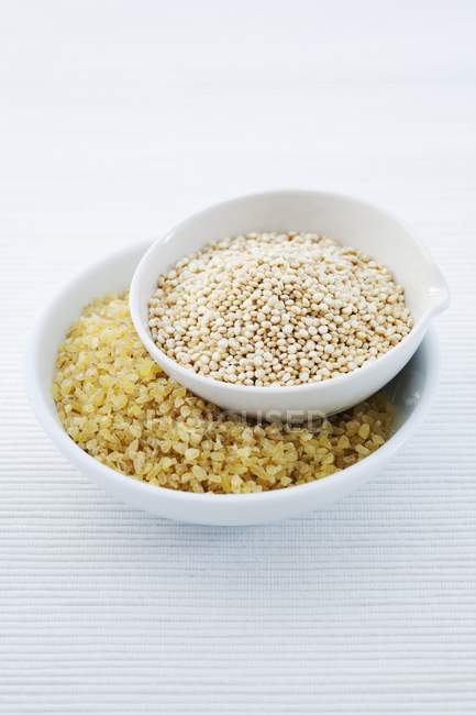 Quinoa seeds and bulgur in bowls. — Stock Photo