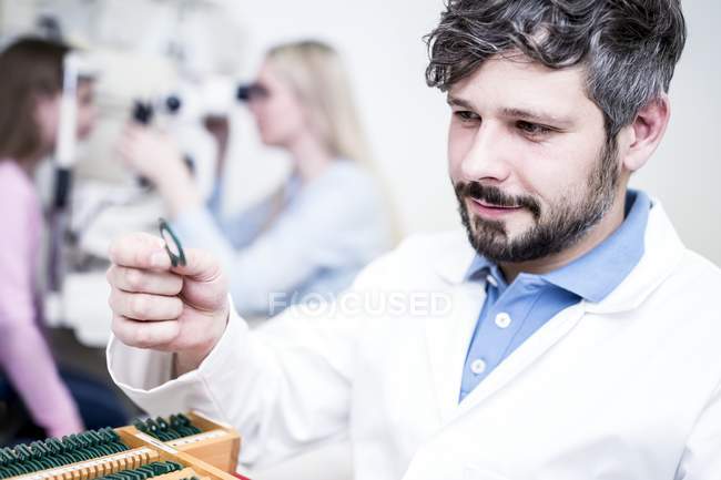 Optometrist holding lens in hand in clinic. — Stock Photo