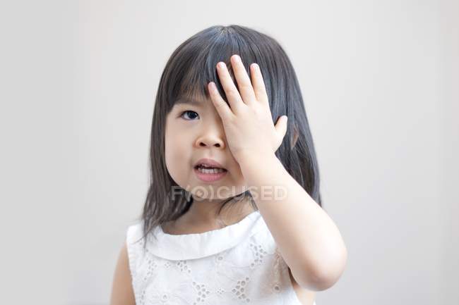 Asiática chica cubriendo ojo con la mano, estudio de tiro . - foto de stock