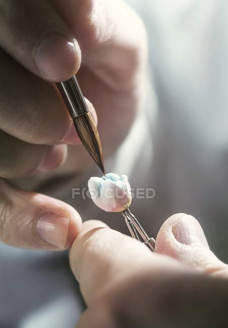 Person painting prosthetic tooth, close-up. — Stock Photo