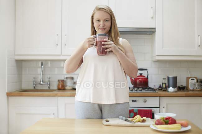 Mulher bebendo smoothie na cozinha — Fotografia de Stock