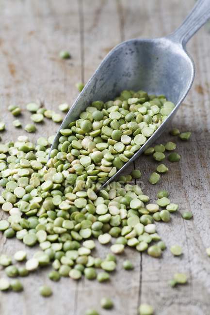 Green split peas on wooden table with scoop. — Stock Photo