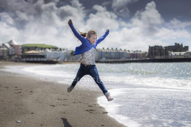 Elemental chica de edad saltando en la playa soleada . - foto de stock