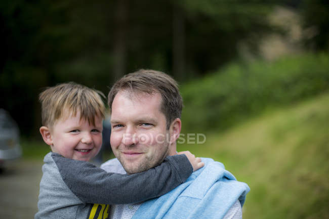 Father holding toddler son outdoors, portrait. — Stock Photo