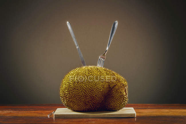 Jackfruit sur la table avec couverts collant dedans . — Photo de stock