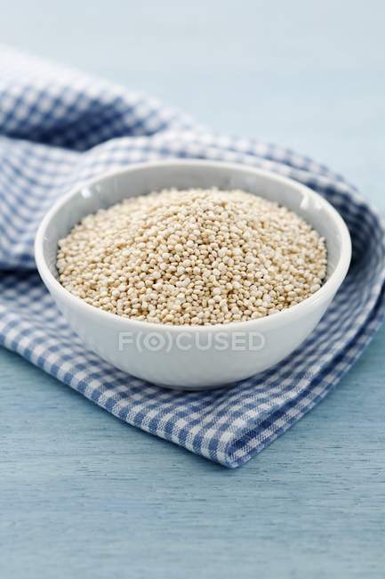 Quinoa seeds in bowl on kitchen towel — Stock Photo