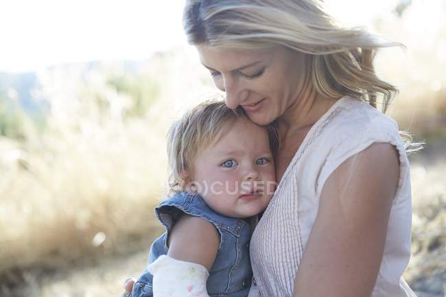 Madre abrazando hija pequeña con brazo en yeso . - foto de stock