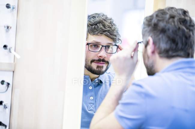 Homme essayant des lunettes dans la boutique optométriste . — Photo de stock