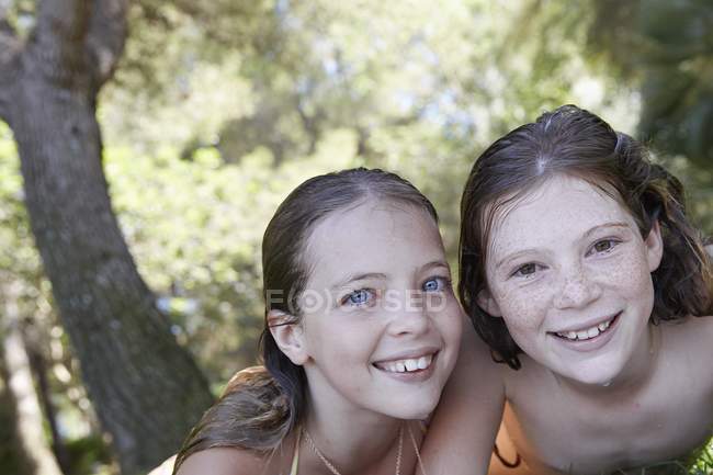 Deux filles préadolescentes souriant à la caméra à l'extérieur, portrait . — Photo de stock