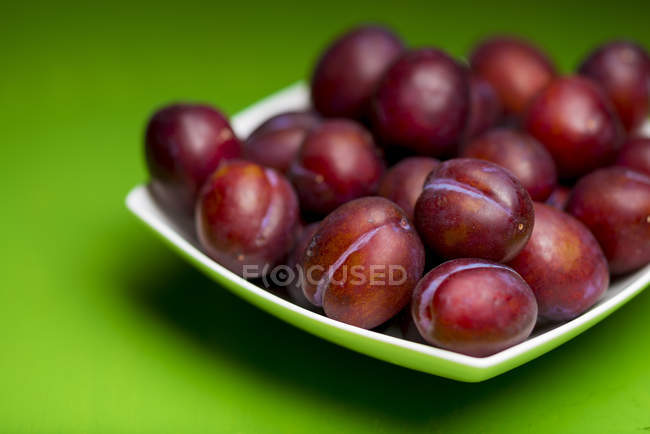 Close-up view of plums on plate, still life. — Stock Photo