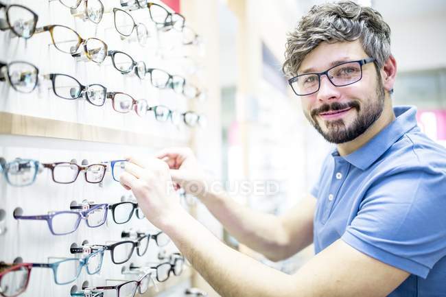 Homem no rack de óculos na loja de optometrista . — Fotografia de Stock