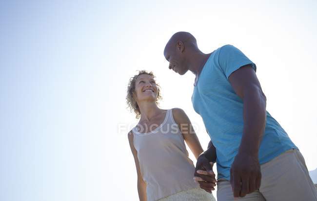 Couple holding hands outdoors, low angle view. — Stock Photo