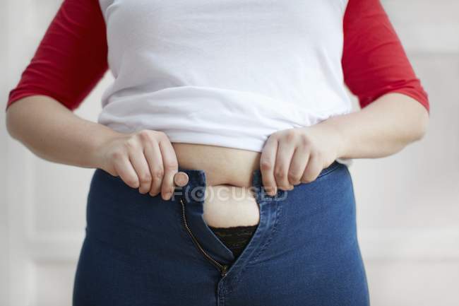 Donna cercando di abbottonare i jeans — Foto stock