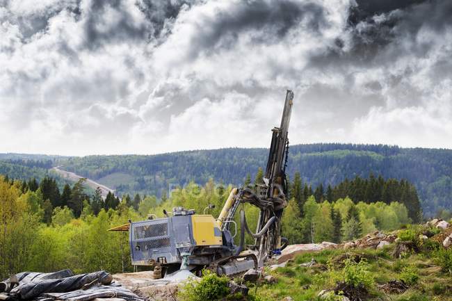 Macchine di perforazione nel paesaggio nuvoloso con foresta . — Foto stock