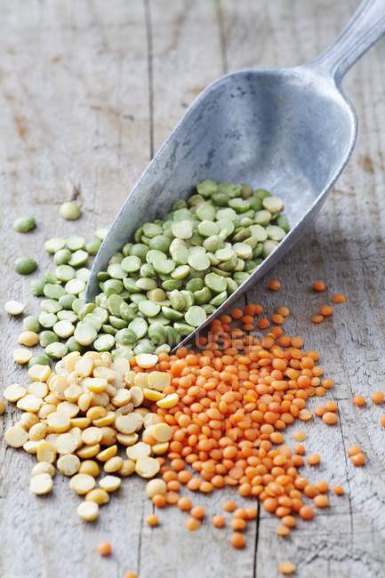 Green split peas, yellow split peas and red lentils in metal grain scoop — Stock Photo