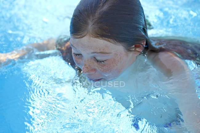 Preteen girl with freckles swimming in pool. — Stock Photo