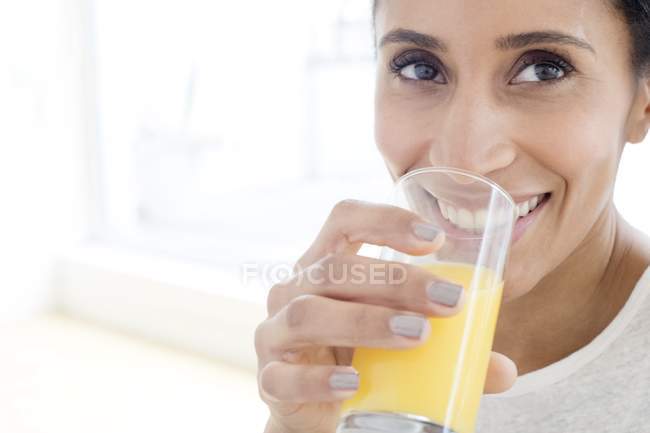 Mitte erwachsene Frau trinkt ein Glas Orangensaft, Portrait. — Stockfoto