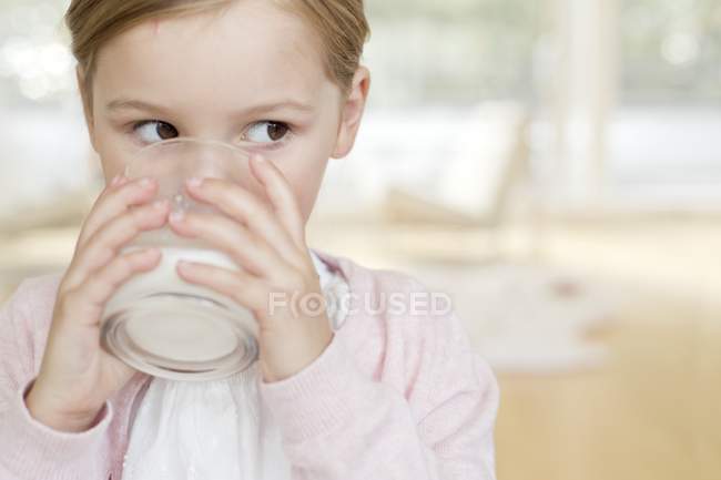 Elementary age girl drinking glass of milk. — Stock Photo
