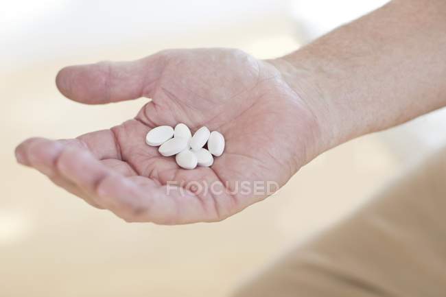 Männliche Hand hält weiße Tabletten in der Handfläche. — Stockfoto