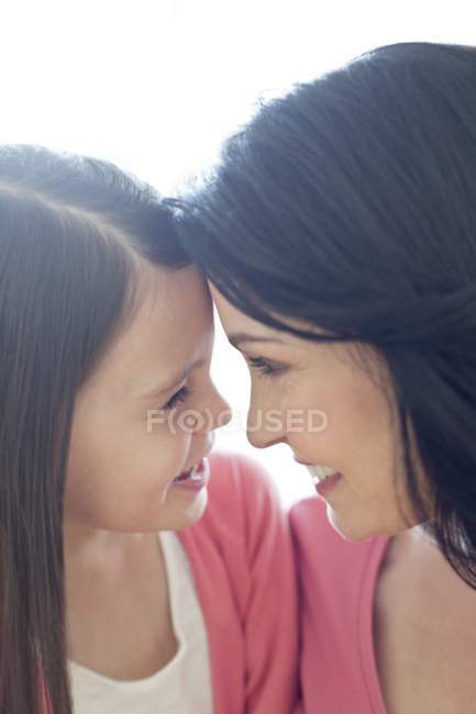 Sorridente madre e figlia faccia a faccia, primo piano
. — Foto stock