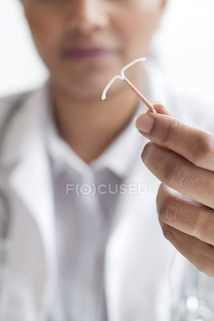 Médica mulher segurando dispositivo intrauterino, close-up . — Fotografia de Stock